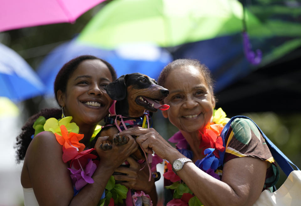 Women pose for a photo with their dog during the "Blocao" dog carnival parade, in Rio de Janeiro, Brazil, Saturday, Feb. 18, 2023. (AP Photo/Silvia Izquierdo)