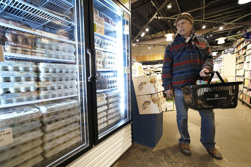 Gregg Fath, of Des Moines, Iowa, looks at eggs in a grocery store cooler, Friday, Feb. 4, 2022, in Des Moines, Iowa. Without much fuss and even less public attention, the nation's egg producers are in the midst of a multi-billion-dollar shift to cage-free eggs that is dramatically changing the lives of millions of hens in response to new laws and demands from restaurant chains. (AP Photo/Charlie Neibergall)