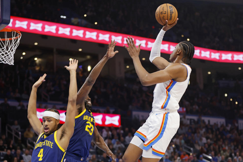 Oklahoma City Thunder forward Jalen Williams, right, shoots over Golden State Warriors forward Draymond Green (23) and guard Moses Moody (4) during the first half of an NBA basketball game Friday, Dec. 8, 2023, in Oklahoma City. (AP Photo/Nate Billings)