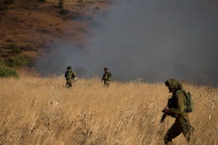 Israeli soldiers patrol next to smoke from a fire caused by a rocket attack in northern Israel, near the Lebanese border, August 20, 2015. REUTERS/JINIPIX