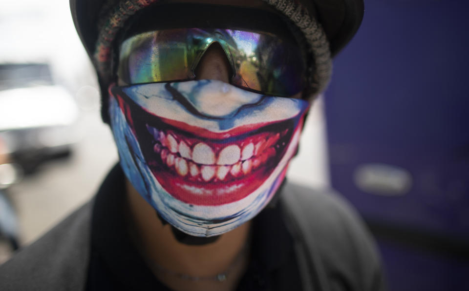 A man wears a mask featuring the smile of comic book character The Joker, amid the spread of the new coronavirus in Caracas, Venezuela, Monday, March 30, 2020. (AP Photo/Ariana Cubillos)