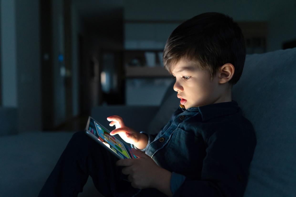 Portrait of a young boy using an app on a digital tablet at home at nighttime â€“ lifestyle