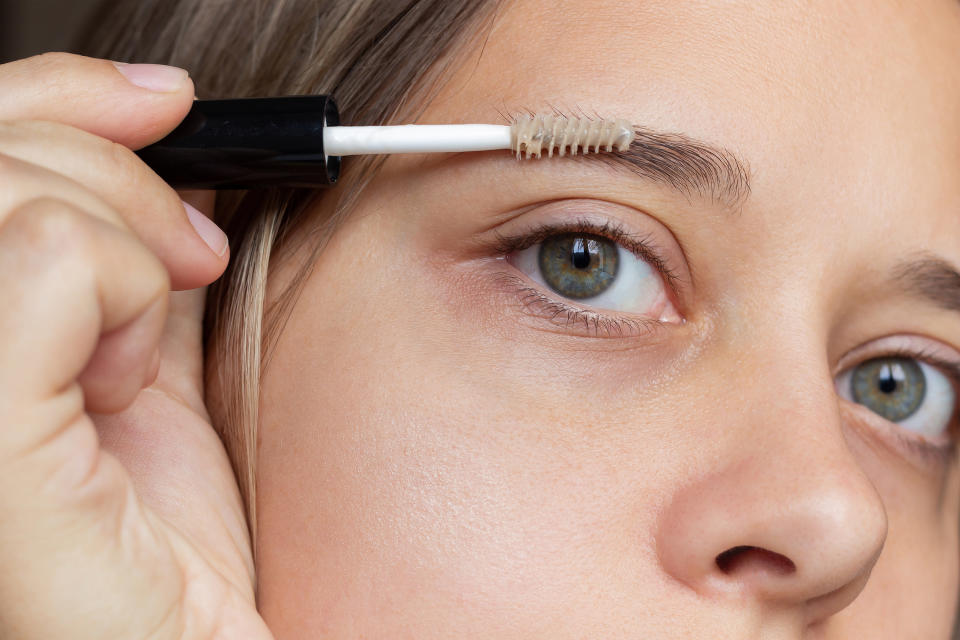 A woman using a spoolie on her eyebrows