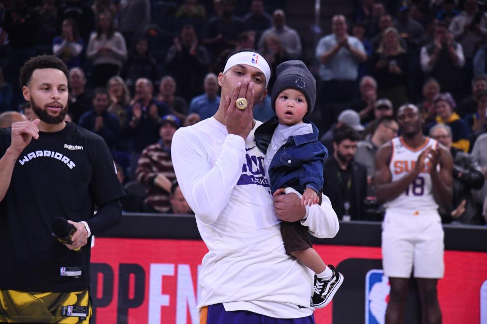 Phoenix Suns guard Damion Lee shows his NBA championship while holding his son and with his brother-in-law and former Warriors teammate, Stephen Curry, by his side. Curry presented Lee his ring before Tuesday's Jan. 10 game at Chase Center in San Francisco.