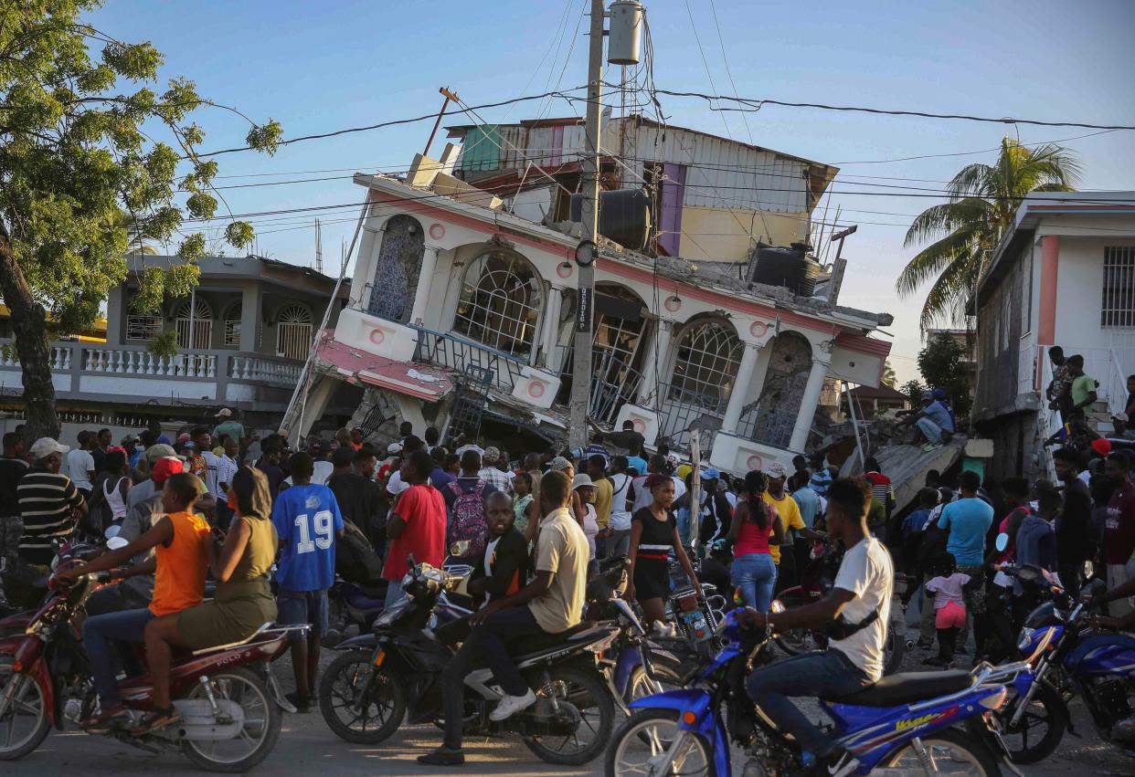 People gather outside the Petit Pas Hotel, destroyed by an earthquake in Les Cayes, Haiti, Saturday, Aug. 14, 2021. A 7.2 magnitude earthquake struck Haiti on Saturday, with the epicenter about 125 kilometers (78 miles) west of the capital of Port-au-Prince, the U.S. Geological Survey said.