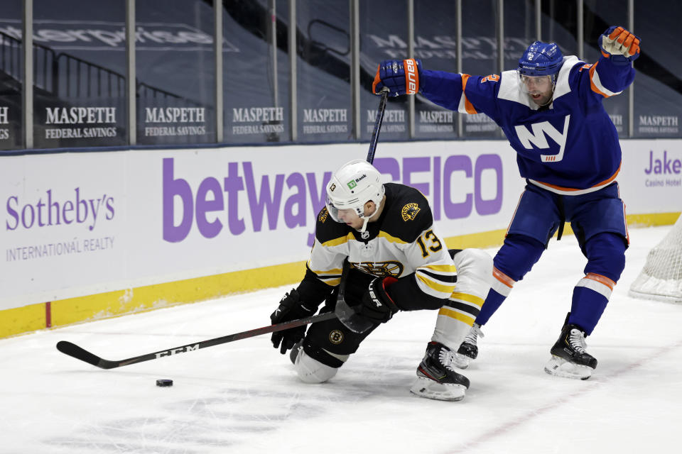 Boston Bruins center Charlie Coyle (13) controls the puck in front of New York Islanders defenseman Nick Leddy during the first period of an NHL hockey game Saturday, Feb. 13, 2021, in Uniondale, N.Y. (AP Photo/Adam Hunger)