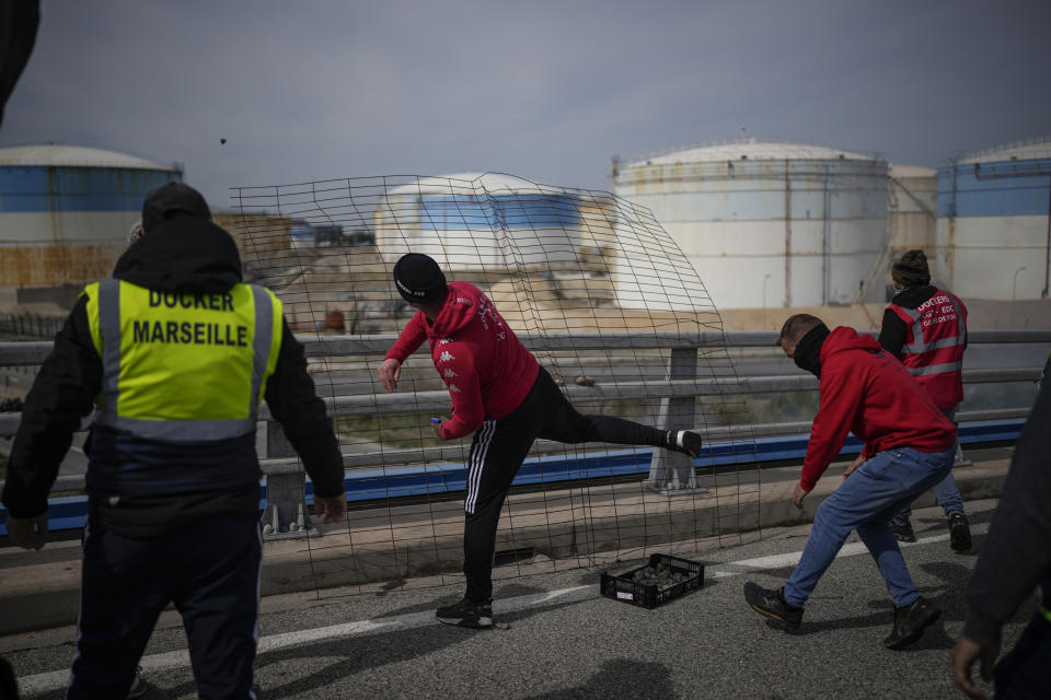 Oil workers throw stones against riot police as they block the access to an oil depot in Fos-sur-Mer, southern France, Tuesday, March 21, 2023. The bill pushed through by President Emmanuel Macron without lawmakers' approval still faces a review by the Constitutional Council before it can be signed into law. Meanwhile, oil shipments in the country were disrupted amid strikes at several refineries in western and southern France. (AP Photo/Daniel Cole)