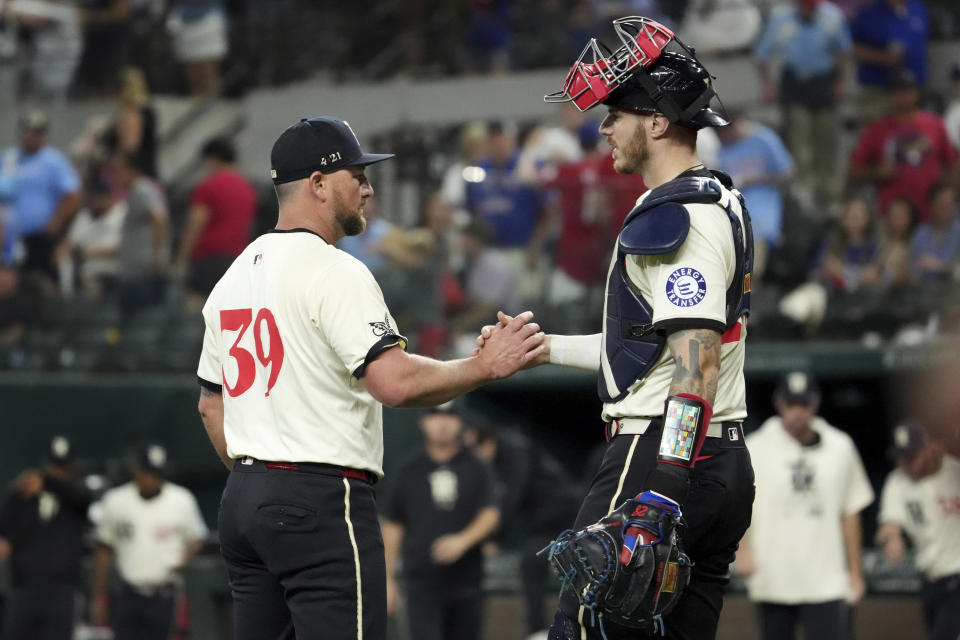 Texas Rangers relief pitcher Kirby Yates (39) and catcher Jonah Heim congratulate each other after the team's victory over the Kansas City Royals in a baseball game Friday, June 21, 2024, in Arlington, Texas. (AP Photo/Jeffrey McWhorter)
