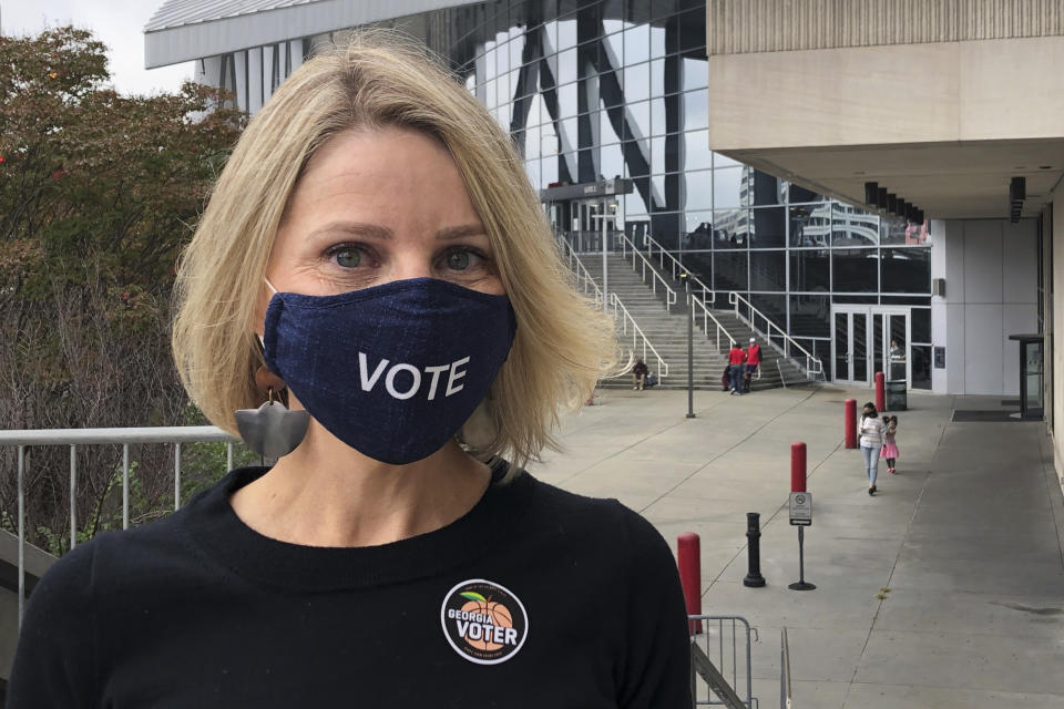 Jen Cox poses for a photo on Thursday, Oct. 15, 2020, after voting early at State Farm Arena in downtown Atlanta. The arena, where the NBA's Atlanta Hawks play, is one of many professional sports venues around the country that has opened its doors for voting or other election-related activities. With dozens of voting machines and ample space for social distancing, they provide a safe and efficient way to vote during the ongoing coronavirus pandemic. (AP Photo/Kate Brumback)