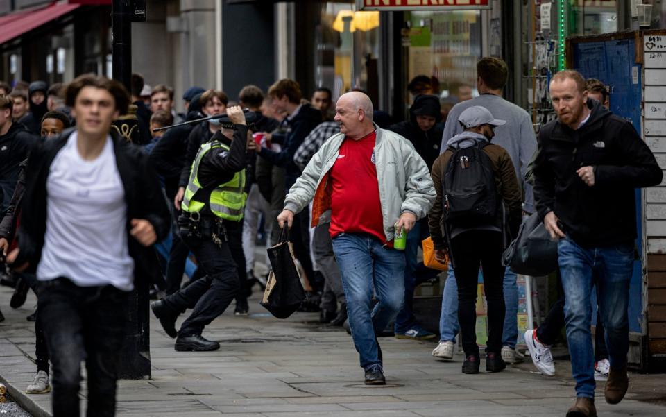 LONDON, ENGLAND - JUNE 18: A policeman tackles a group of England fans as they attempt to run towards Scotland fans gathered in Leicester Square on June 18, 2021 in London, England. England v Scotland is not only the oldest fixture in the world, they have also played one another more than any other two international teams. Their first encounter was played in 1872 at Hamilton Crescent, Glasgow and their 115th match today at Wembley for Euro 2020. (Photo by Rob Pinney/Getty Images)  - Rob Pinney/Getty Images