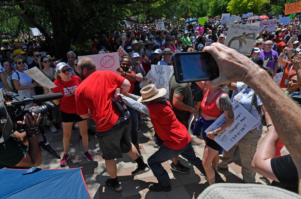 A pro-gun man is pushed away from the crowd as they wait outside the NRA convention in Houston Friday May 27, 2022.