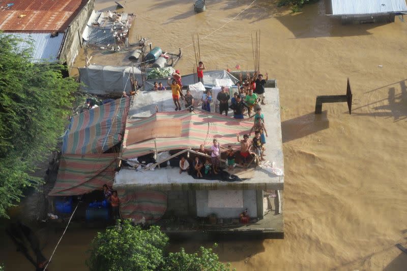 People stand on a roof of a building after Typhoon Vamco resulted in severe flooding, in the Cagayan Valley region