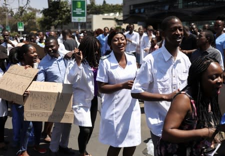 Doctors sing and hold placards during a protest over the disappearance of the leader of their union in Harare