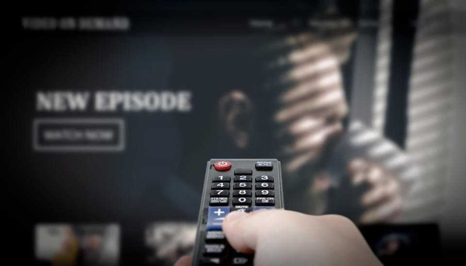 VOD service on television. Man watching TV, streaming service, video on demand, remote control in hand.