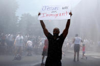 <p>Jonathan Reed of Silver Spring, Maryland, holds up a sign as he stands in a spray of water from a fire truck during rally by immigration activists to protest against the Trump Administration’s immigration policy outside the White House in Washington,D.C., June 30, 2018. (Photo: Joshua Roberts/Reuters) </p>