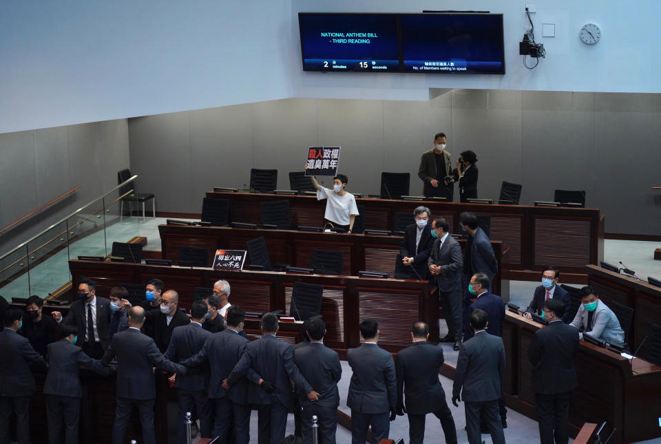 Pro-democracy lawmaker Tanya Chan, center, holding a placard reading "A murderous regime stinks for ten thousand years" as they protest at the main chamber of the Legislative Council in Hong Kong, Thursday, June 4, 2020. Hong Kong’s legislature approved a contentious bill Thursday that makes it illegal to insult the Chinese national anthem. The legislation was approved after pro-democracy opposition lawmakers tried to disrupt the vote. (AP Photo/Vincent Yu)