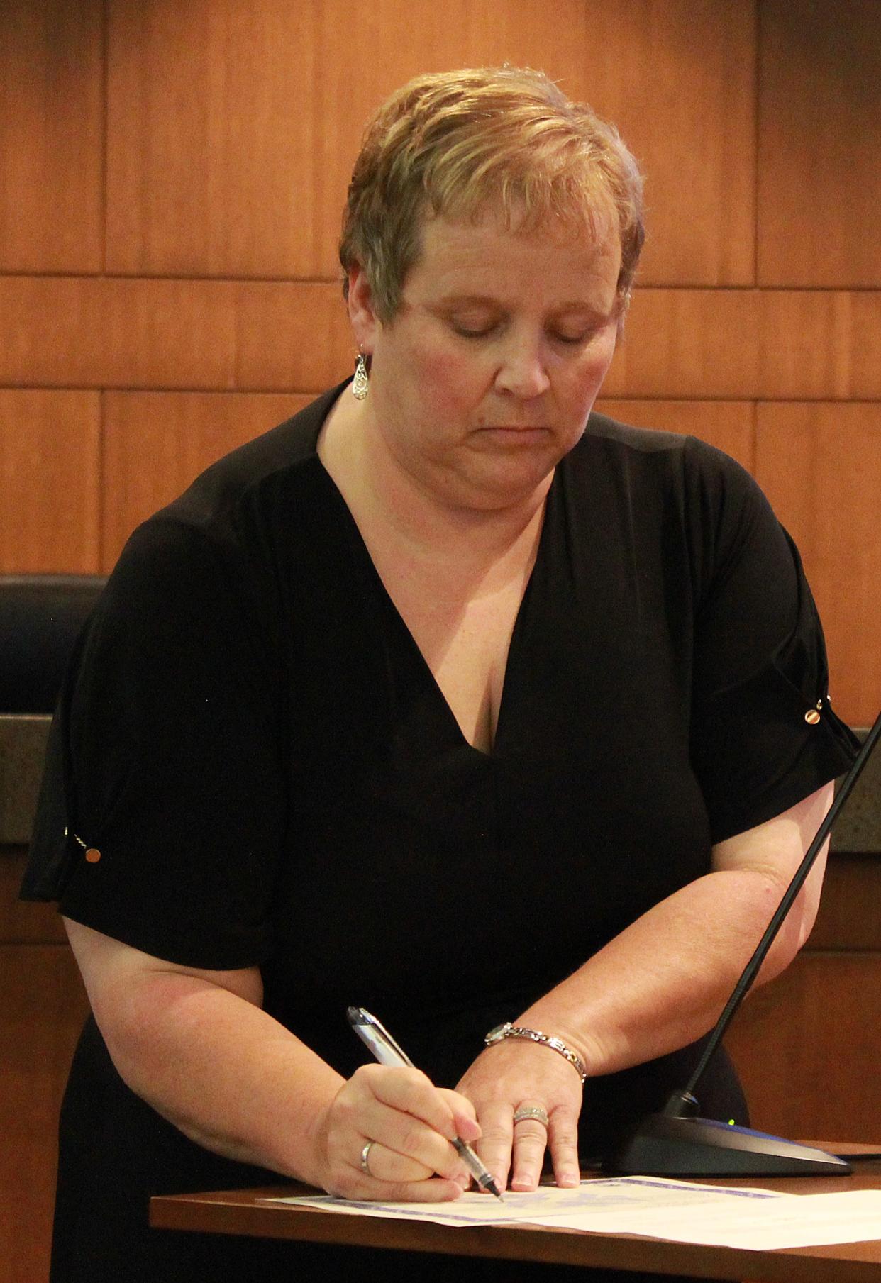 Kathy Baker, who served as interim human resources director for the City of Columbia, signs her name after she was sworn in as the permanent human resources director Tuesday at City Hall.