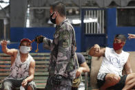 A Philippine policeman talks to violators of a stricter community lockdown to prevent the spread of the new coronavirus as they hold them inside a basketball court in Manila, Philippines on Tuesday May 5, 2020. (AP Photo/Aaron Favila)