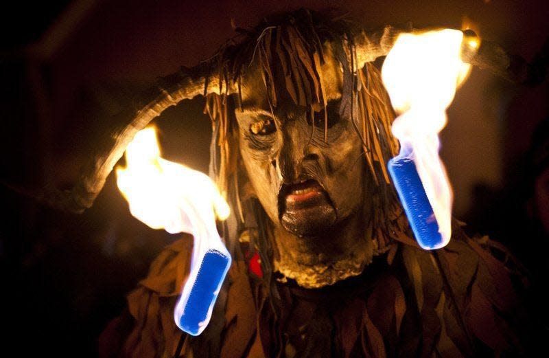 A Krampus named Pook blows flames for the crowd during the 2014 Krampus parade in downtown Bloomington.