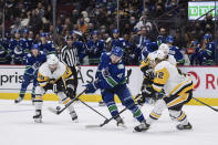 Vancouver Canucks' Quinn Hughes (43) vies for the puck against Pittsburgh Penguins' Sam Lafferty (18) and Kasperi Kapanen (42) during the second period of an NHL hockey game Saturday, Dec. 4, 2021, in Vancouver, British Columbia. (Darryl Dyck/The Canadian Press via AP)