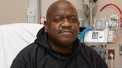  Close-up picture of Rick Slayman. He is sat on a hospital bed and wearing what looks like a black sweatshirt. . 