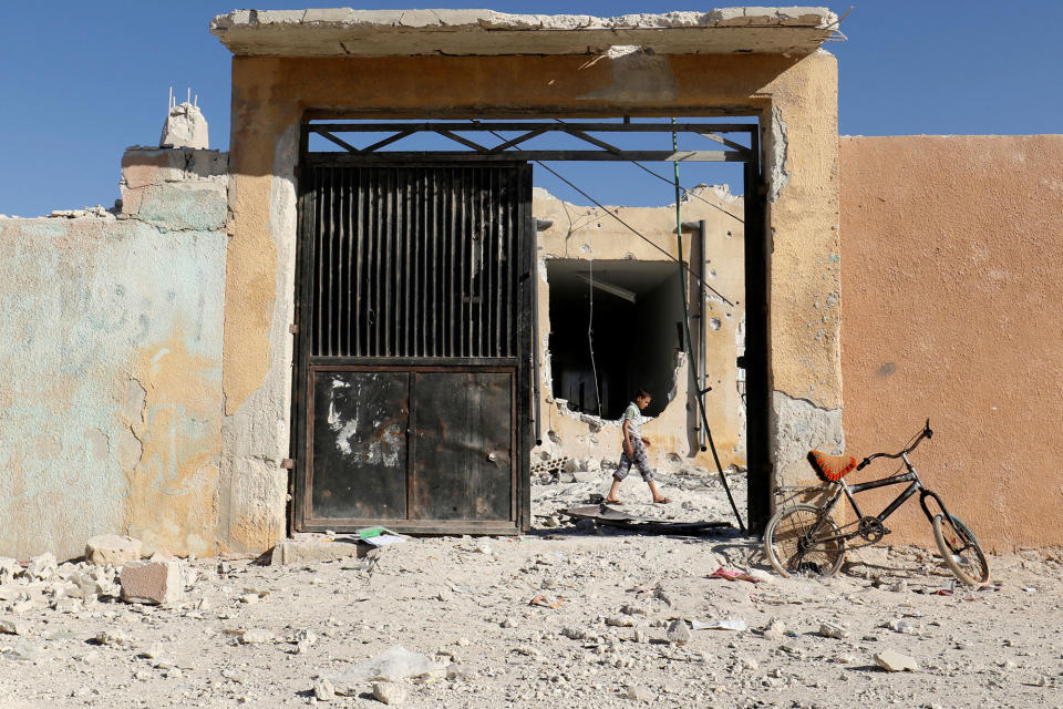 A boy inspects a damaged site after shelling in the rebel held town of Hass, south of Idlib province