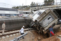 Police officer and train workers stand by a derailed train Tuesday Oct.16, 2018 near Sidi Bouknadel, Morocco. A shuttle train linking the Moroccan capital Rabat to a town further north on the Atlantic coast derailed Tuesday, killing several people and injuring dozens, Moroccan authorities and the state news agency said. (AP Photo/Abdeljalil Bounhar)