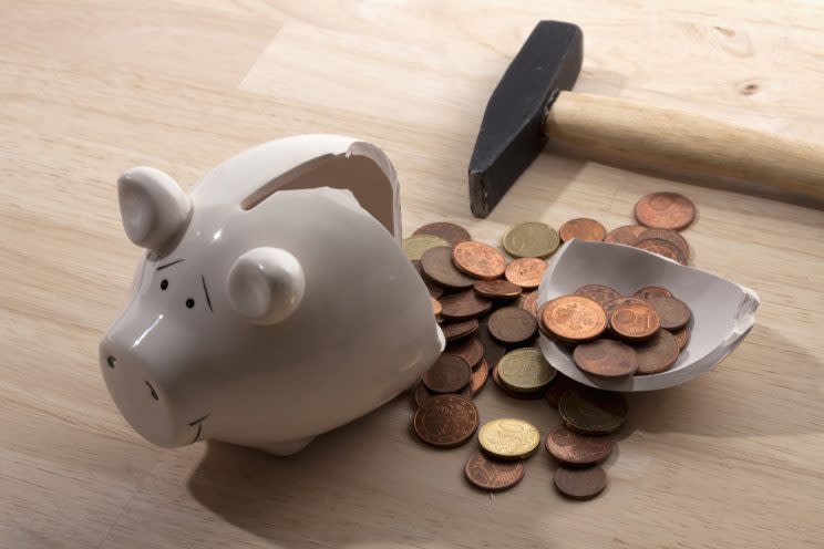 A hammer lying next to a broken piggy bank with Euro coins spilling out