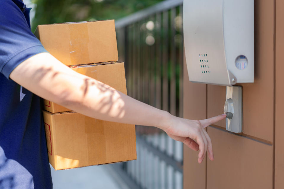 Delivery service courier ringing the house doorbell with boxes in hands