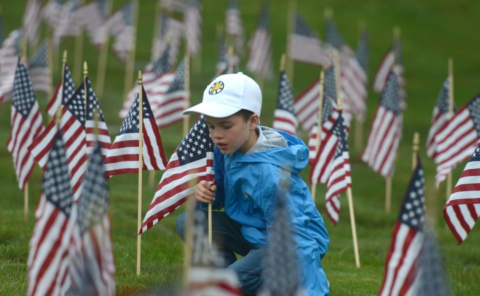 Eight-year-old Liam Lima-Carty is surrounded by his efforts placing headstone flags at the National Cemetery in Bourne on Saturday where hundreds of volunteers gathered to place tens of thousands of flags on all the veterans' graves in honor of Memorial Day. 
Steve Heaslip/Cape Cod Times
