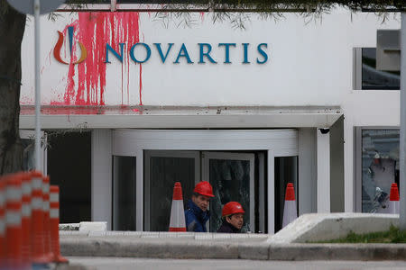 Workers clean the entrance of the Swiss drugmaker Novartis offices after protesters threw paint and smashed windows, in Athens, Greece, February 25, 2018. REUTERS/Costas Baltas