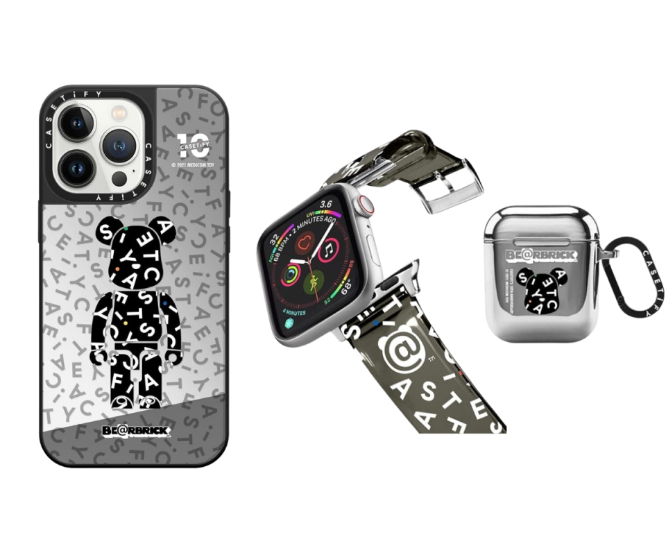 A chrome iPhone case with a black BE@RBRICK bear in the middle, an apple iWatch with a khaki strap and CASETiFY's logo jumbled on it, and a chrome apple airpods case with a black bear's face silhouette in the middle against a white background.