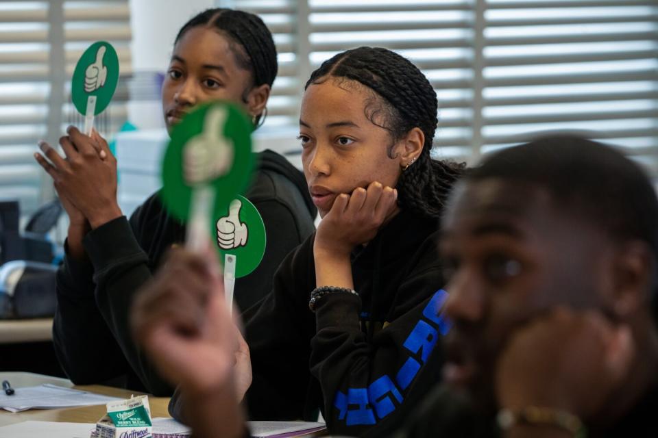 Students raise placards to indicate a "yes" answer to a question.