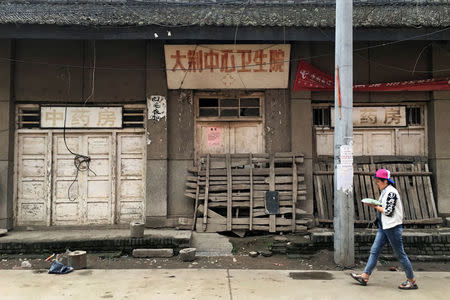 A woman walks past a boarded-up local medical centre in a village in rural Shaanxi province, China, June 11, 2017. REUTERS/Sue-Lin Wong