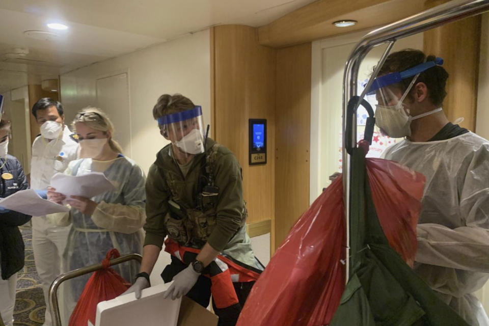 In this Thursday, March 5, 2020, photo, released by the California National Guard, Guardian Angels, a group of medical personnel with the 129th Rescue Wing, working alongside individuals from the Centers for Disease Control and Prevention, don protective equipment after delivering virus testing kits to the Grand Princess cruise ship off the coast of California. Passengers on a cruise ship off the California coast were instructed to stay in their cabins as they awaited test results Friday that could show whether the coronavirus is circulating among the more than 3,500 people aboard. (Chief Master Sgt. Seth Zweben/California National Guard via AP)