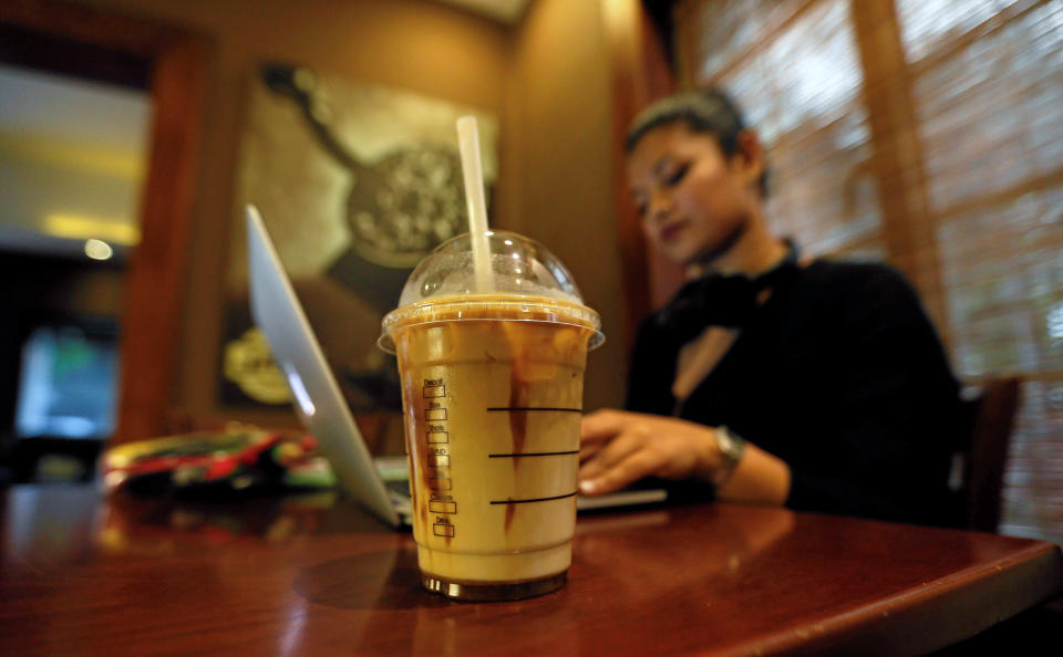 A cup of iced coffee is seen, as a woman works on her laptop, at Java Lounge coffee shop in Colombo, Sri Lanka May 4, 2017. (REUTERS/Dinuka Liyanawatte)