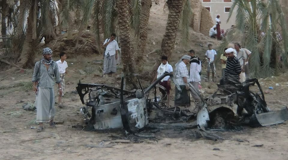 Villagers surround a car hit by a drone strike in the village of Khashamir in 2012. Photo: Supplied