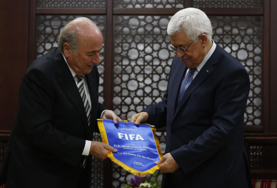 Palestinian president Mahmoud Abbas (R) receives a gift from FIFA President Sepp Blatter in the West Bank city of Ramallah May 26, 2014. REUTERS/Mohamad Torokman (WEST BANK - Tags: SPORT SOCCER POLITICS)