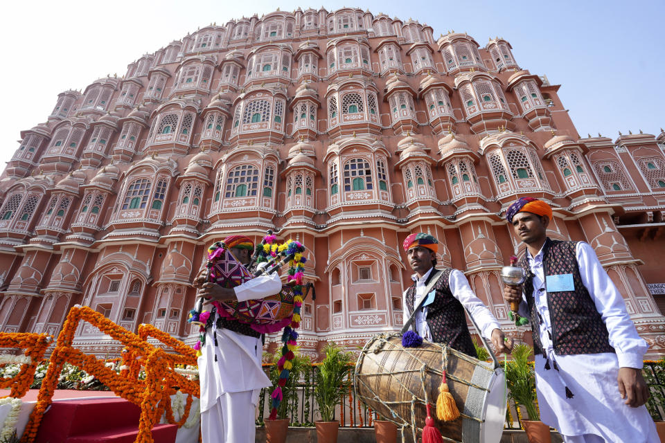 Rajasthani folk artists stand near the city landmark Hawa Mahal Palace, as they await the arrival of French President Emmanuel Macron in Jaipur, Rajasthan, India, Thursday, Jan.25, 2024. Macron will be the chief guest at India's annual republic day parade in New Delhi on Friday. (AP Photo/Deepak Sharma)