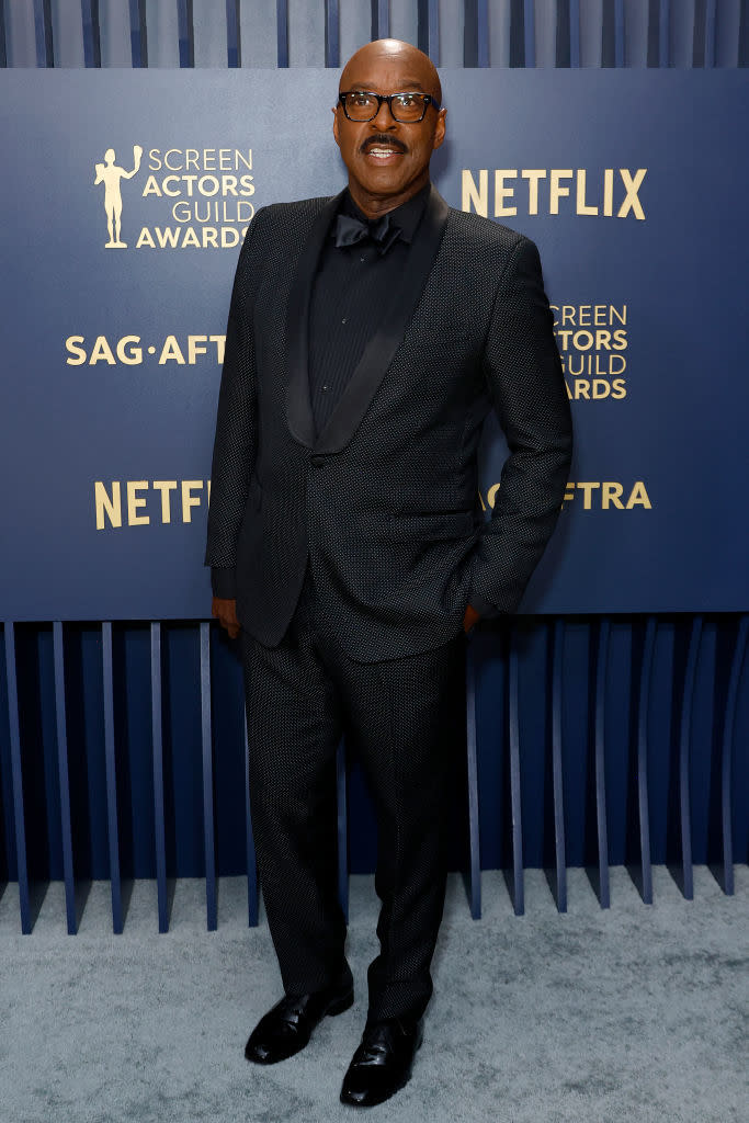Courtney B. Vance stands in a tailored suit with a patterned jacket and bow tie