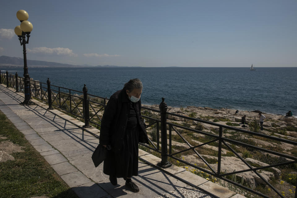 A woman wearing a face mask to prevent the spread of Covid-19 walks alongside a coast at Piraeus port town near Athens, Saturday, March 27, 2021. According to Greek authorities more than 1.5 million doses of the vaccine have been administered so far in the country, with nearly 1 million people receiving at least one jab. (AP Photo/Yorgos Karahalis)