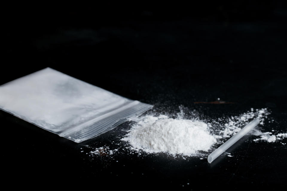 ketamine drugs and plastic straw on bag of white powder on black wood background.Drug epidemic concept.