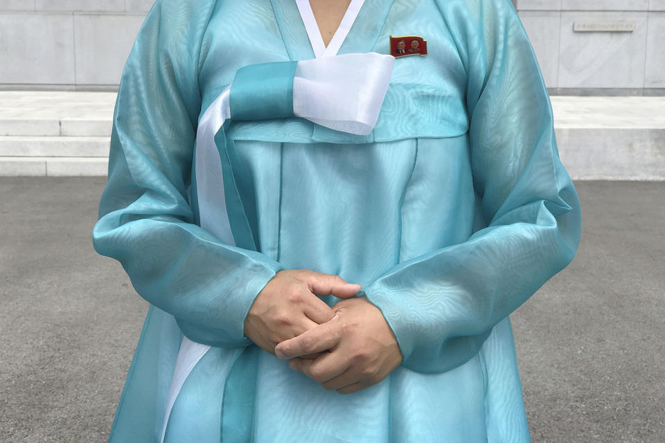 <p>A factory guide in a traditional Korean dress with the faces of the late North Korean leaders Kim Il Sung and Kim Jong Il pinned above her heart on the left of her dress, speaks to visiting media in Pyongyang, North Korea, July 26, 2017. (Photo: Wong Maye-E/AP) </p>