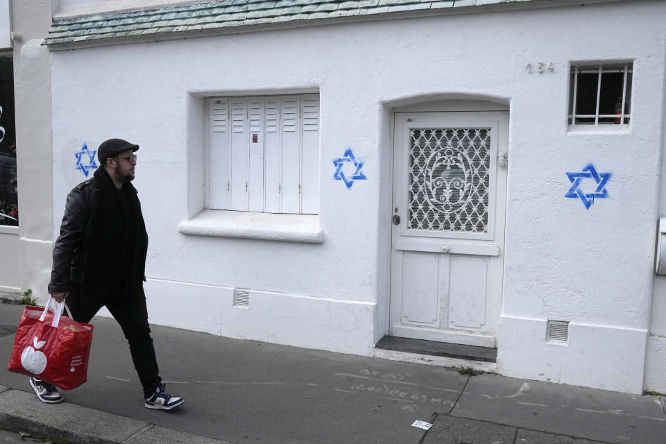 ARCHIVO - Un hombre camina frente a Estrellas de David pintadas en un muro de París, el 31 de octubre de 2023. (AP Foto/Michel Euler, archivo)