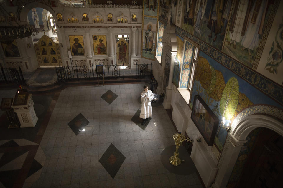 A Russian Orthodox church servant waves a censer during a religious service inside an empty church due to coronavirus pandemic in Moscow, Russia, Saturday, May 30, 2020. Moscow, which accounted for about half of all infections, ordered an easing of the tight lockdown in place since late March, saying that non-food stores, dry cleaners and repair shops can reopen on Monday. (AP Photo/Alexander Zemlianichenko)
