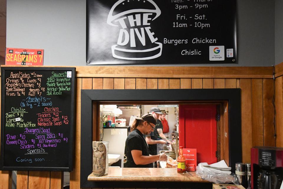 Chris Oines is seen cooking a burger through the pickup window at The Dive pop-up restaurant in the Gaslight Lounge on Wednesday, June 29, 2022, in Sioux Falls.