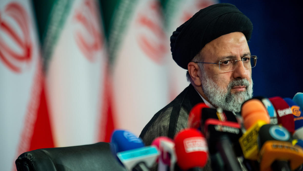 Ebrahim Raisi gazes past a gaggle of microphones