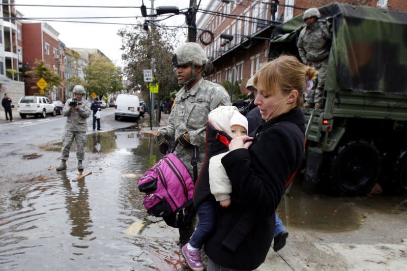 Natalie Vuckovic and her baby Rosalie are rescued from flooded streets by U.S. Army National Guard troops a day after Hurricane Sandy hit Hoboken, N.J. in 2012. File Photo by John Angelillo/UPI