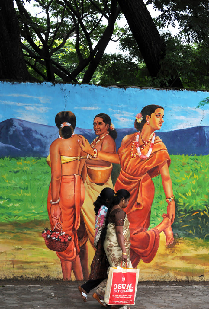 Indian women pass a wall mural in Bangalore.<br> AFP PHOTO/Dibyangshu Sarkar