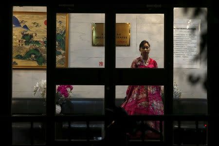 A woman wearing traditional costume waits for customers behind the doors of a North Korean restaurant in Beijing, China, April 12, 2016. REUTERS/Damir Sagolj